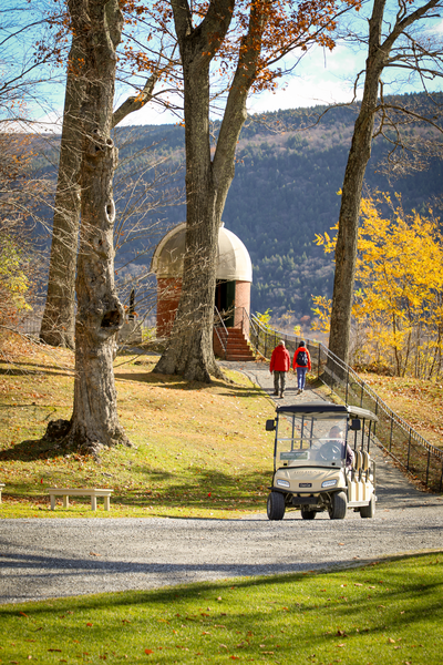 A golf cart sits in front of an autumn scene at Hildene.