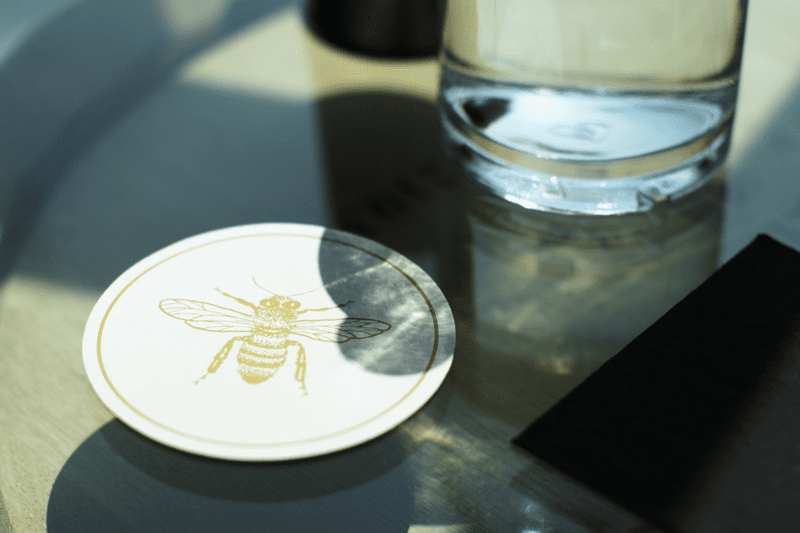 A detail shot of a coaster with a bee graphic at Caledonia Spirits.