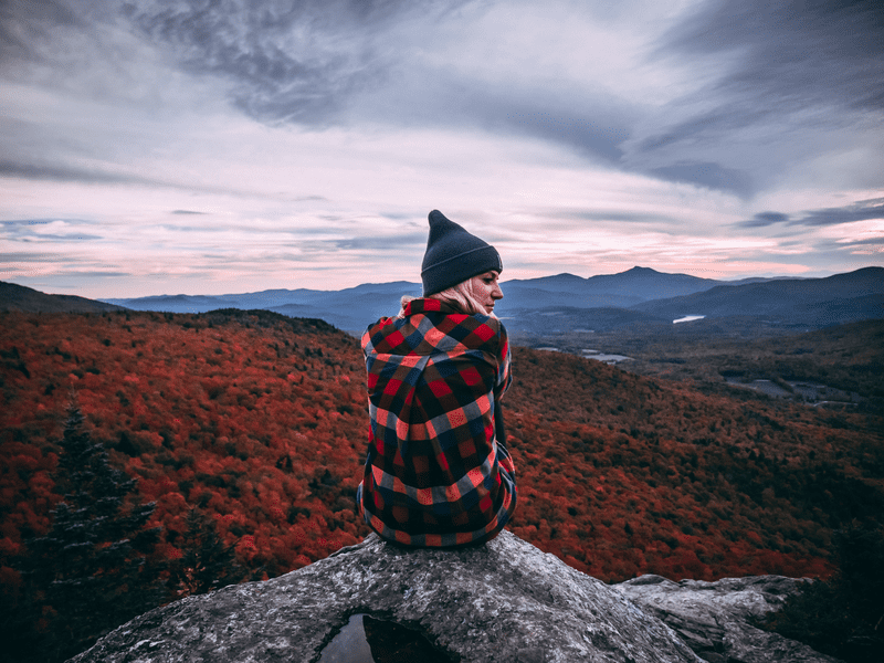 A hiker enjoys the view at the summit of Stowe Pinnacle, in autumn.