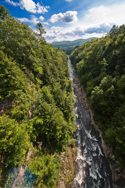 A river flows through a deep canyon surrounded by steep cliffs and trees.