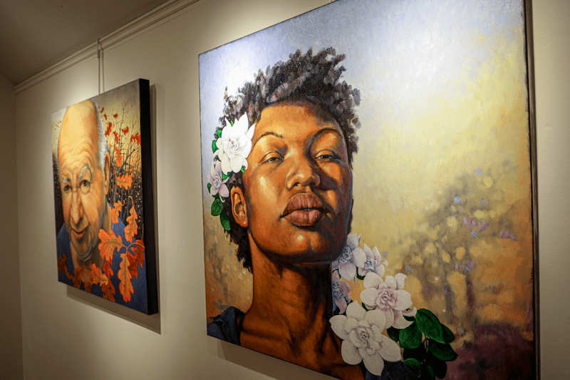 Paintings on a gallery wall of people’s faces with flowers.