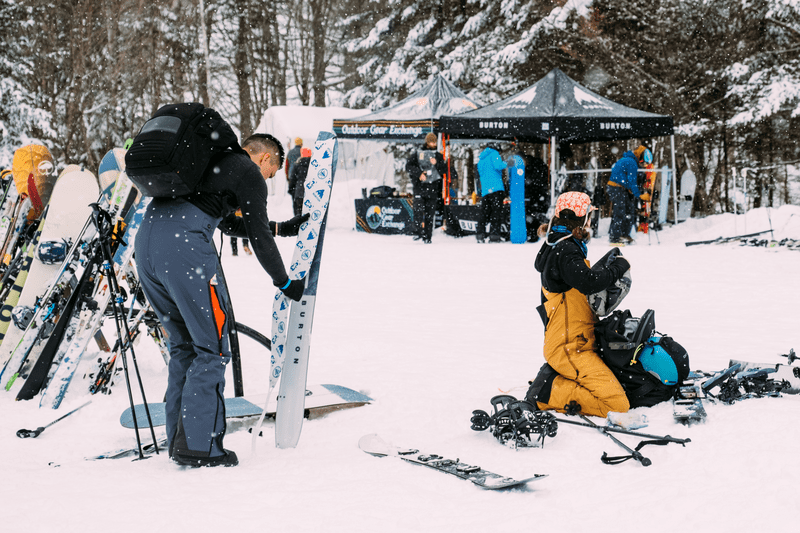 Splitfest participants prep ski gear during snowfall.