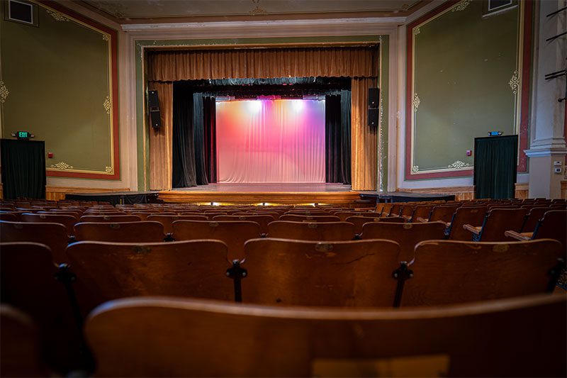 The stage of a performing arts theater is seen from the seats.