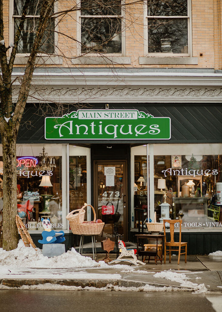 A sign that says “Main Street Antiques” on a storefront in the winter.