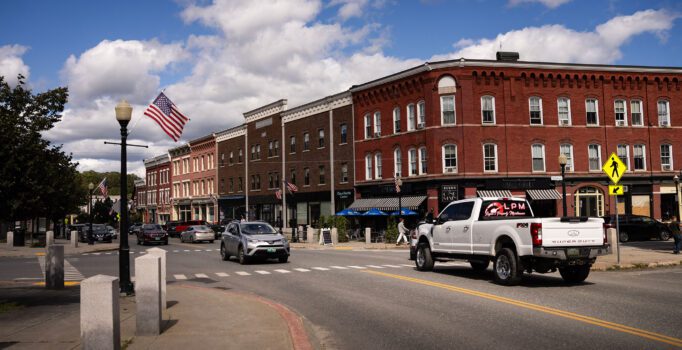 Old brick buildings line a street with cars.