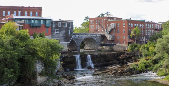 A river running between historic buildings connected by a stone bridge.