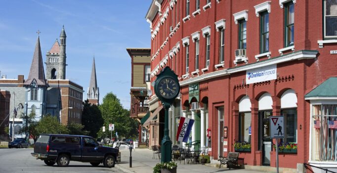 A historic downtown with streets lined with red brick buildings is viewed on a sunny day.
