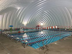An empty indoor pool covered by a large white tent.