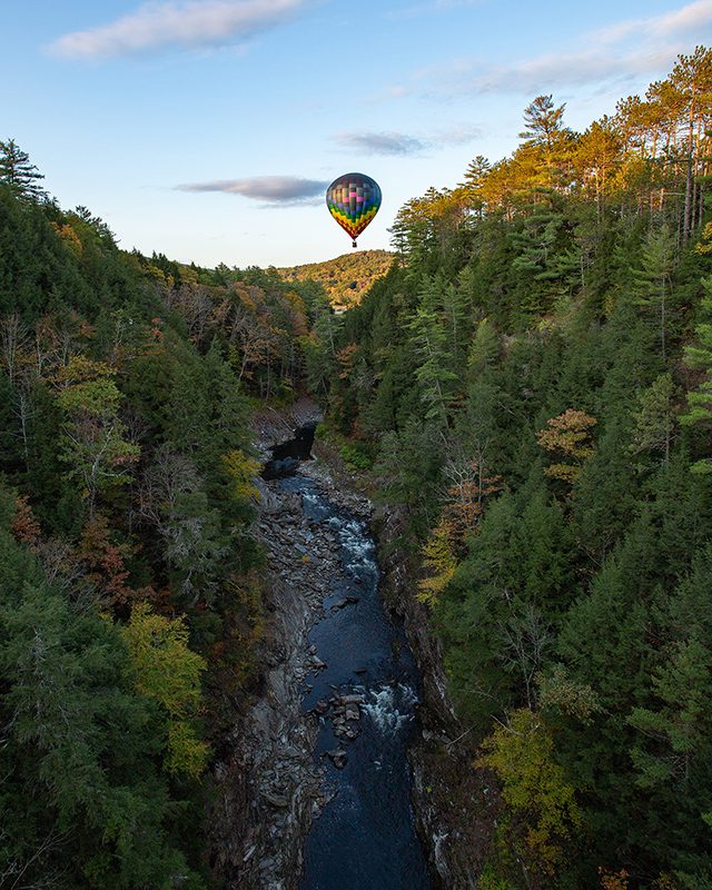 A hot air balloon floats over a gorge.