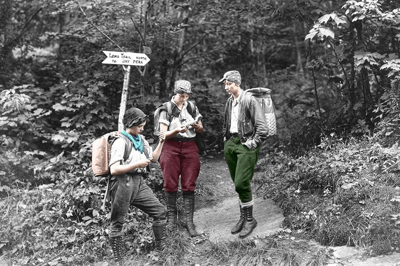 Vintage photo of three women pioneers in Vermont's Long Trail are visible in the woods on the trail.