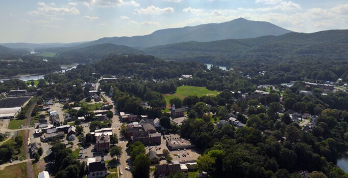 From above, a view of a rural town with mountains in the back.