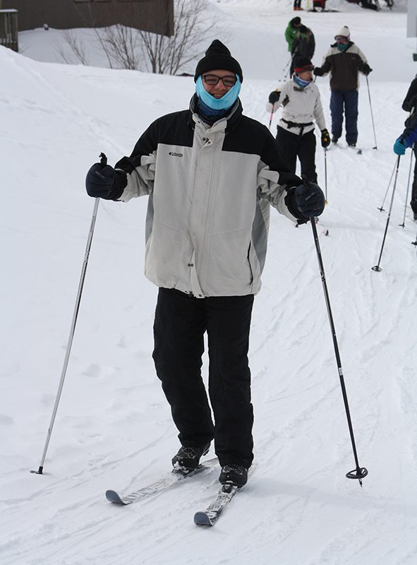 A person skis and smiles while looking at the camera.