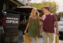 Two people walk past a restaurant with a Brewery Open sign.