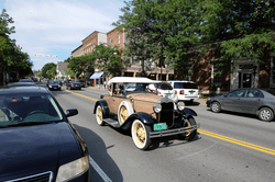 An antique car drives down a road.