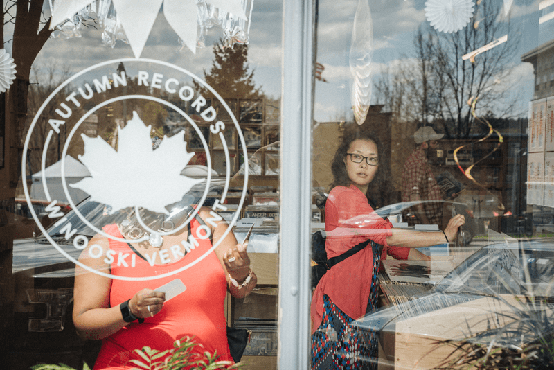 A portrait of patrons through the window display of Autumn Records, in Winooski, Vermont.