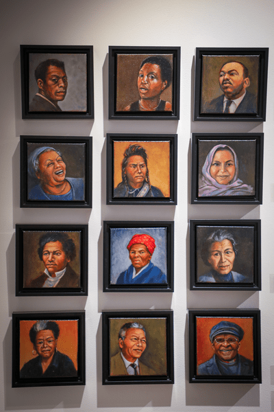 Painted portraits hang on a wall.
