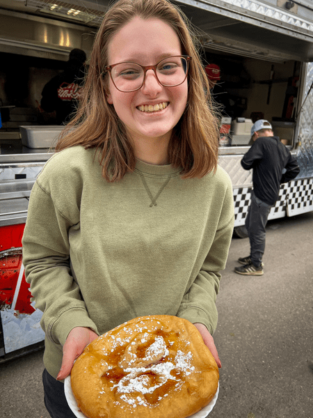 A person presents fried dough covered in Vermont Maple Syrup at the Vermont Maple Festival.