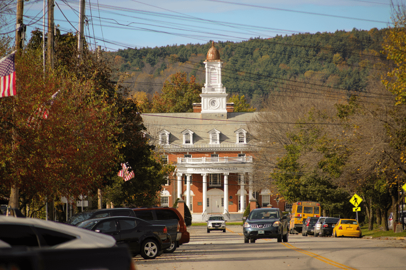 Cars parked along the road of a quiet Poultney streetscape.