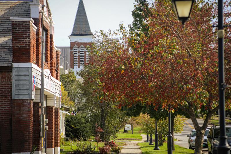 A historic downtown sidewalk in the late fall with a church on one side and brick buildings along the walking path.