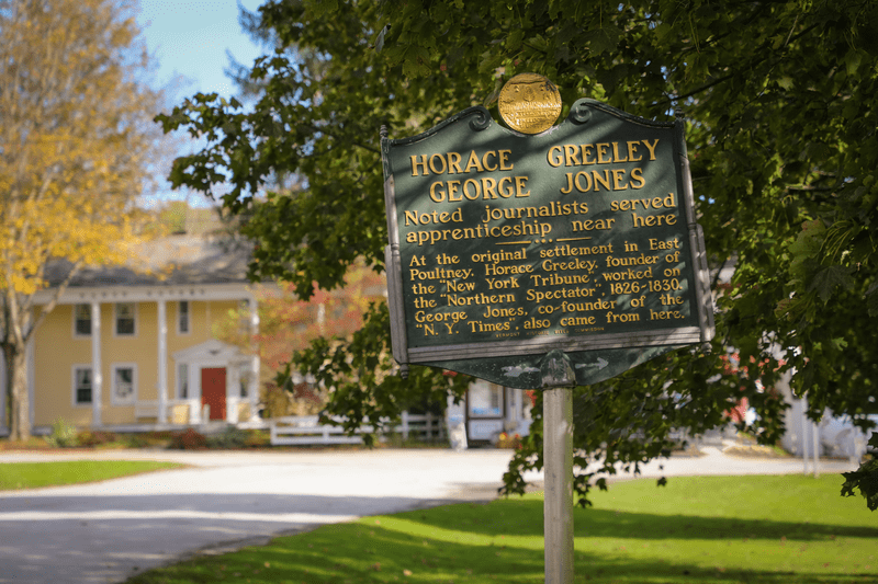 The historic marker for Horace Greeley George Jones, highlighted by the sun.