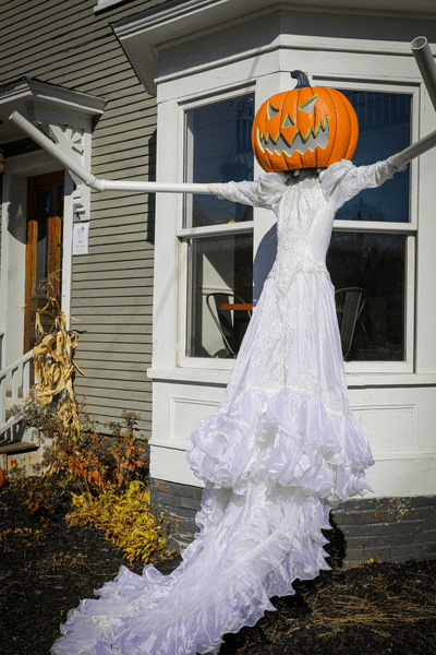 A Halloween display presents a scarecrow in a wedding dress with a pumpkin head.