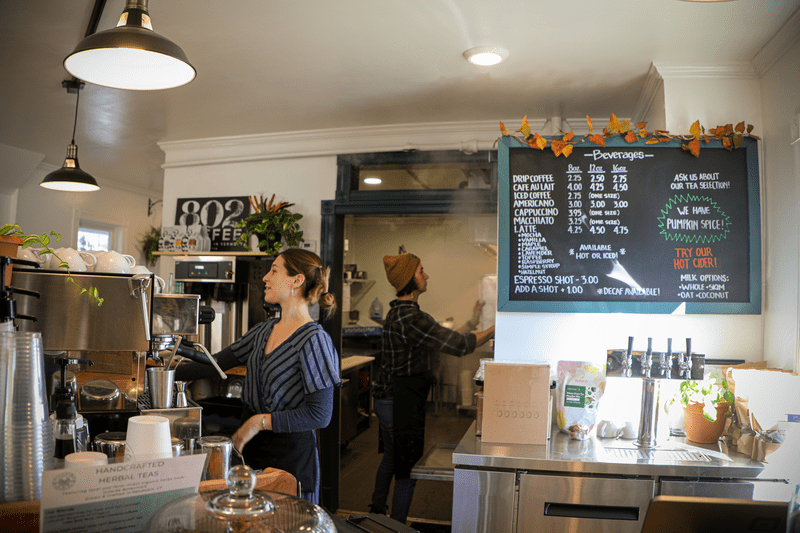 Two people staff the counter at a local coffee shop.