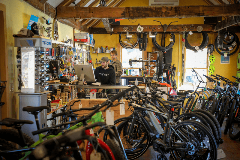 Two people review the desk counter computer at a bike shop.