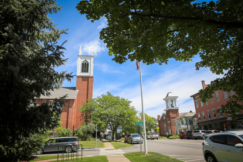 A historic downtown with a stately church spire and brick buildings lining the street.