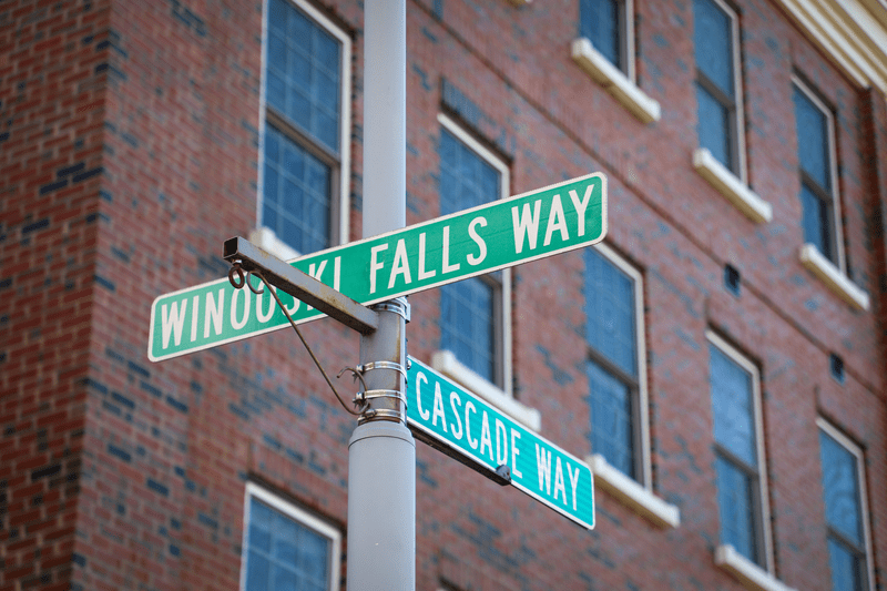 Street signage contrasted with brick at the intersection of Winooski Falls Way and Cascade Way in Winooski, Vermont.