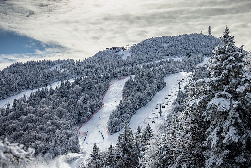 A snowy mountain with ski runs and a chair lift.