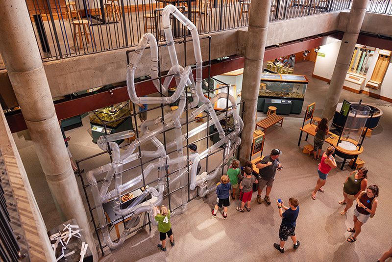 Seen from above, a group of people look at a science exhibit in an indoor science museum.