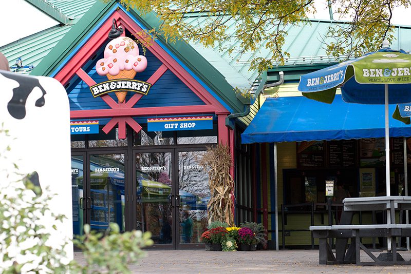 A factory seen from outside with a stylized ice cream cone and a sign reading Ben & Jerry’s, Tours, and Gift Shop.