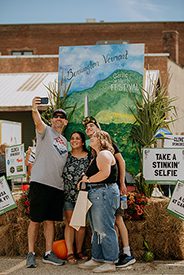 Group of people take a selfie in front of a sign that reads Take a stinkin' selfie.