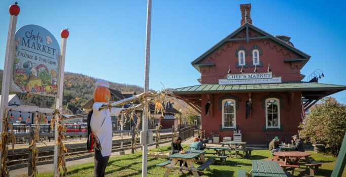 A red brick building in front of an outdoor lawn with picnic tables and a Chef's Market sign.