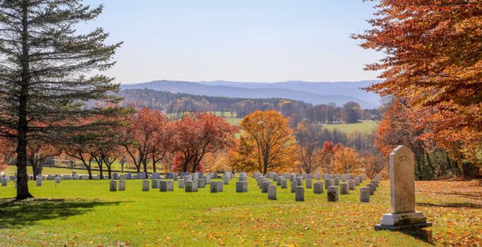 Rows of stone markers dot the landscape, surrounded by trees in fall color.