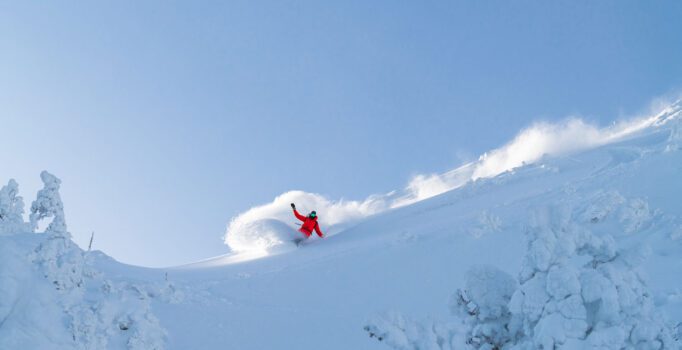 A person snowboards down a powdery mountain.