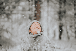 A kid looks up at falling snow.