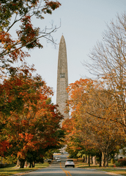 Seen from below, a large stone monument rising above trees in the fall.