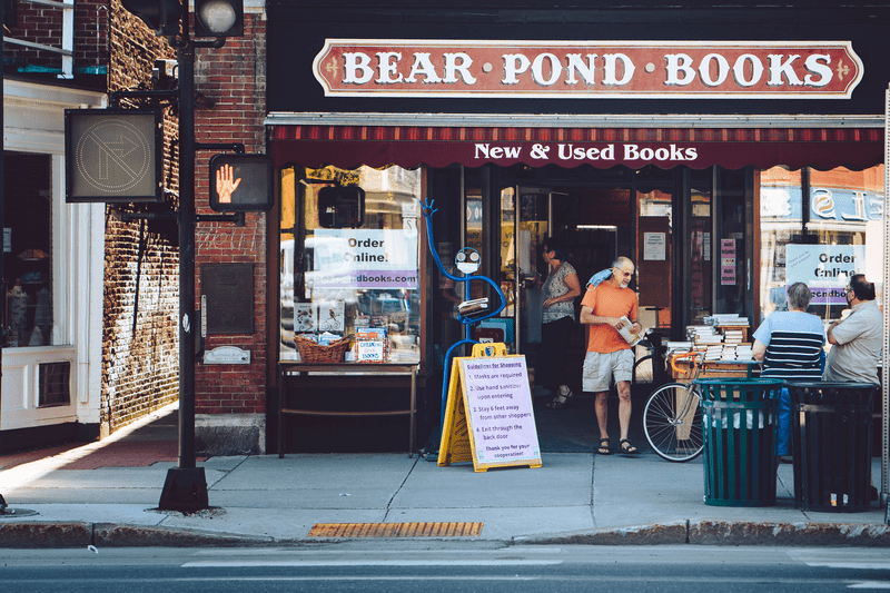 A person leaves a store with a sign that reads Bear Pond Books.