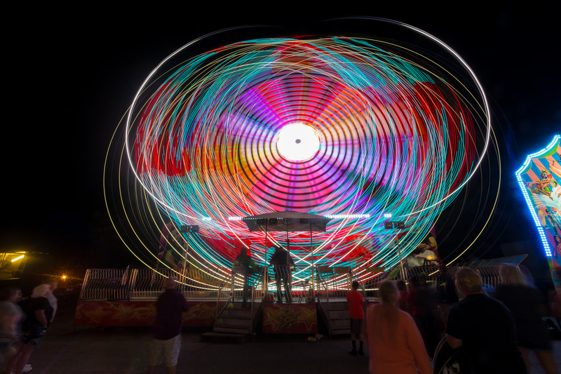 A long exposure image of a Ferris wheel at night, creating circular colored lines against a night sky.