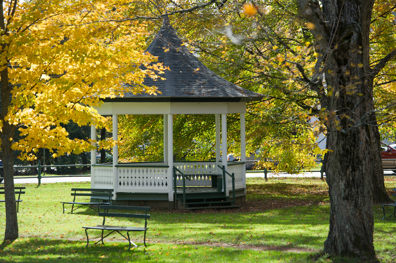 A gazebo sits empty in a park on a fall day.