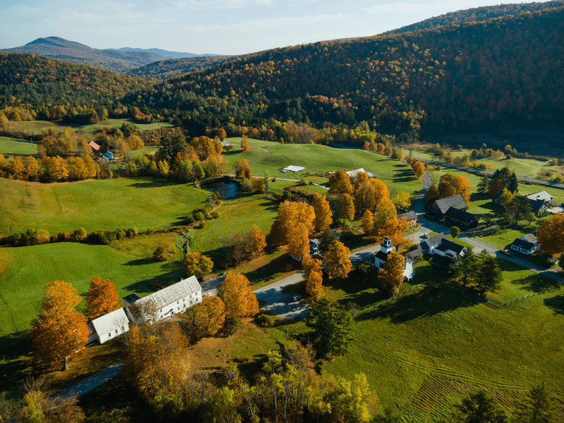 Seen from above, a sprawling mountain farm with green fields in the fall.