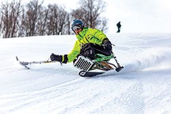A person uses adaptive skis to ski down a mountain.