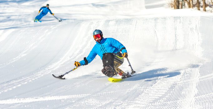 A person uses adaptive skis on a downhill slope.