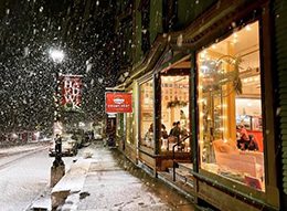 A lit up storefront on a snowy night.
