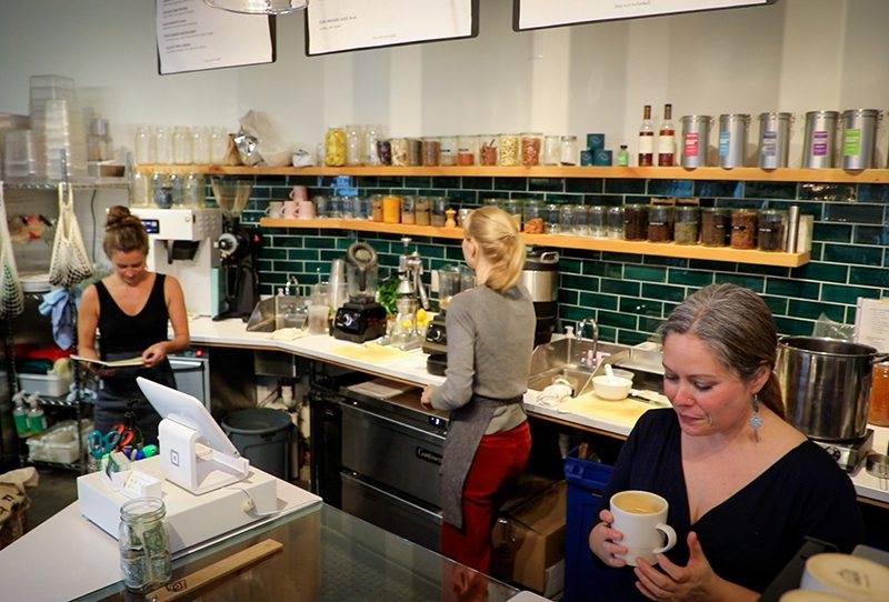 Three people standing behind a counter at a cafe or restaurant.