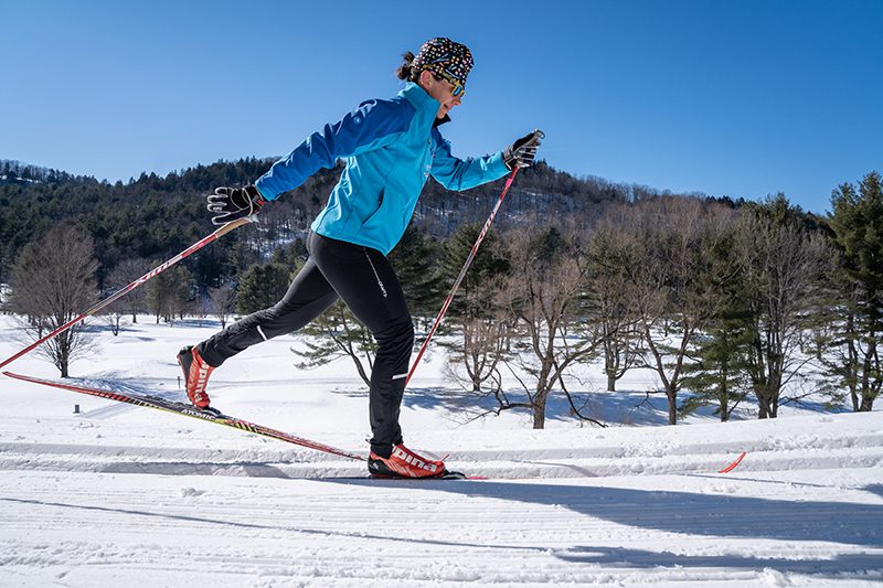 A person cross-country skis on a sunny day.