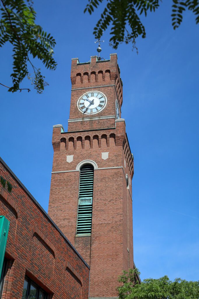 Seen from below, a large brick clock against a blue sky.