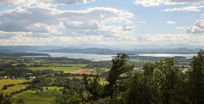 The view from the top of a mountain with another mountain and a lake visible in the distance.
