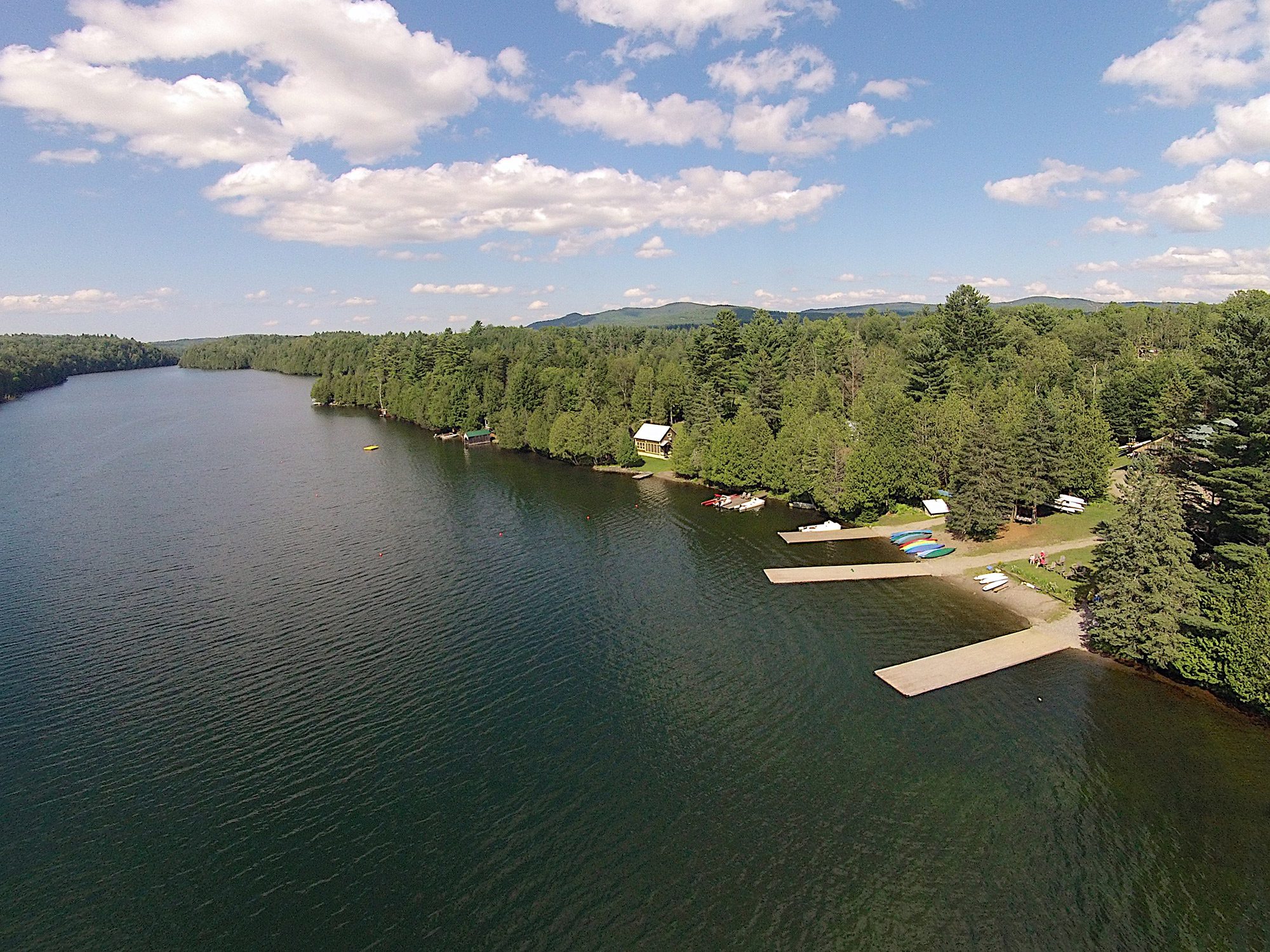 Seen from above, docks on a lake in the summer with forests surrounding. 